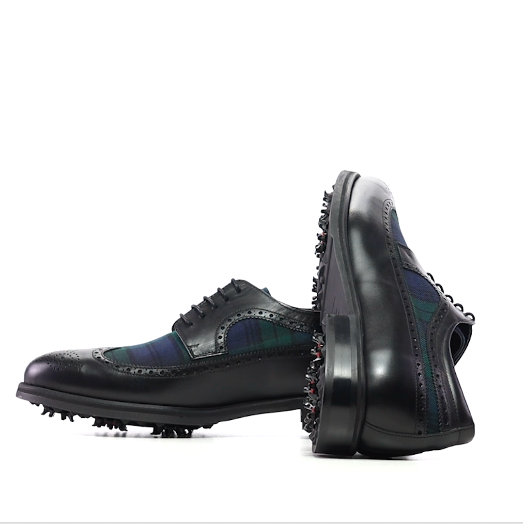 A pair of handmade black leather golf shoes with Black Watch tartan on the vamps, side on view showing the lace-up closure and round toes.
